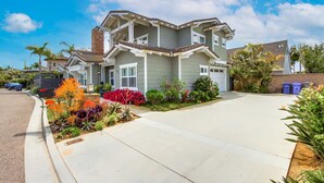 A two-story house with a front yard, driveway, and a garage. - Outdoor Living Area * A/C * Custom Built Home (Encinitas)