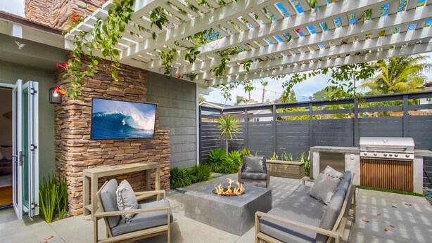 An outdoor patio with a stone wall, a fire pit, and outdoor furniture. - Outdoor Living Area * A/C * Custom Built Home (Encinitas)