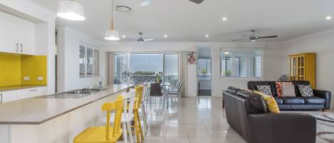 Amplia sala de estar con un sofá, una mesa de comedor con sillas y una zona de cocina con barra.