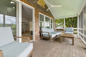 A covered outdoor seating area with wooden furniture and a ceiling fan.