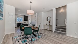 A modern dining area with a round table, teal chairs, and a geometric rug. - A Family Relaxing Vacation House, 3 bedrooms2.5 bathrooms for up to 8 people (Calgary)
