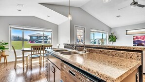Una cocina moderna con una isla grande, taburetes de bar y vistas a una zona residencial.