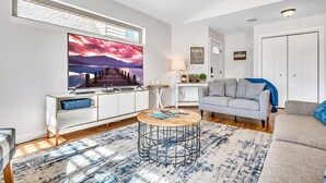 Una sala de estar moderna con un televisor grande, un sofá, una mesa de centro y vistas a un muelle.