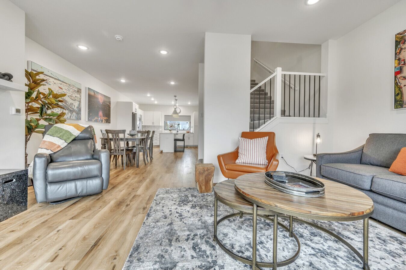 A modern living room with a leather sofa, a dining area, and a staircase.
