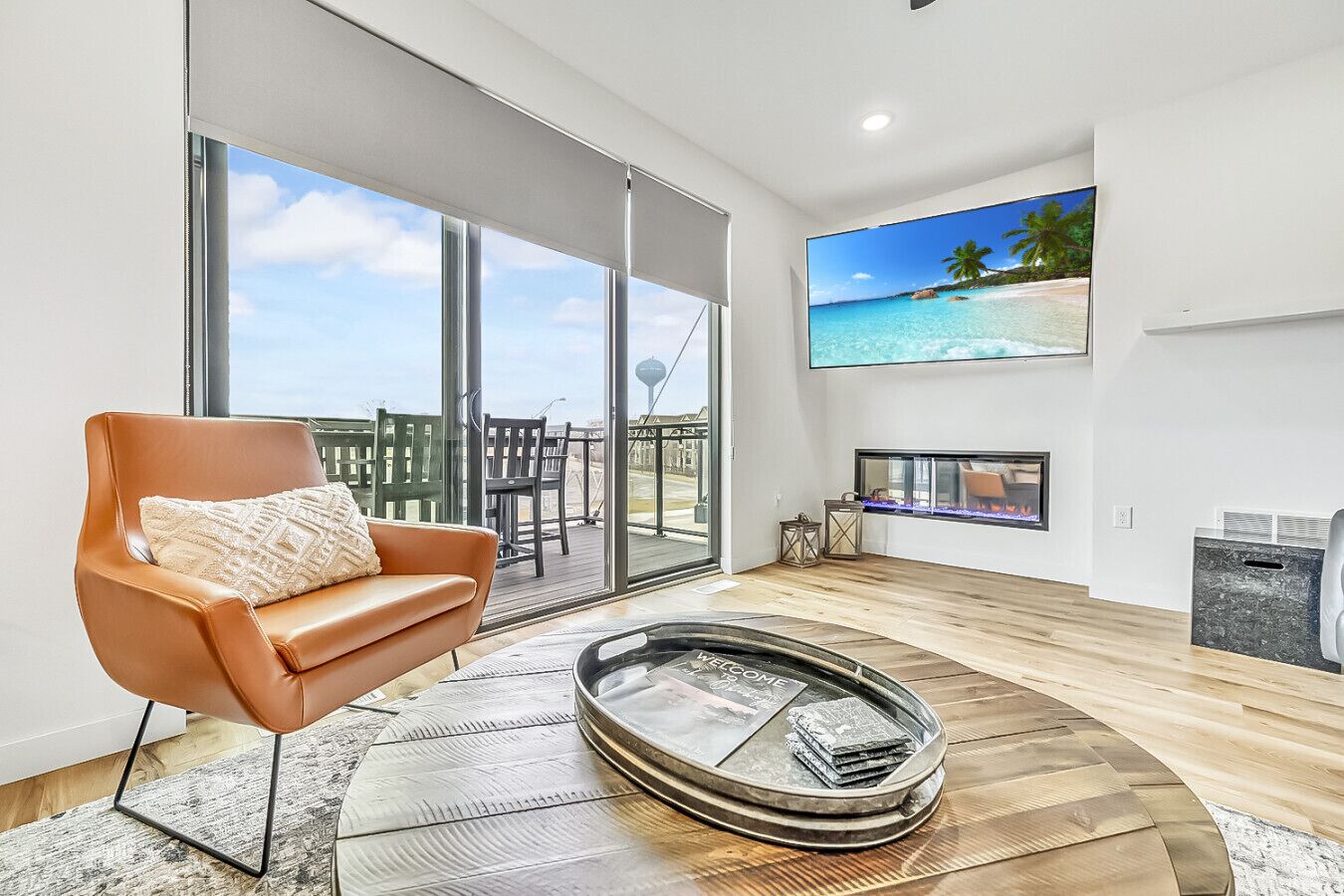 A modern living room with a leather sofa, a glass fireplace, and a large TV on the wall.