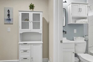 Un baño con un mueble blanco, un inodoro y un lavamanos.