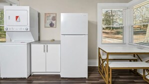 Una cucina compatta con lavatrice-asciugatrice integrata, frigorifero e zona pranzo con vista panoramica da ampie finestre.
