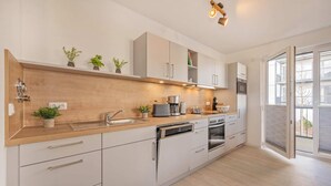 Une cuisine moderne avec un plan de travail en bois, des appareils électroménagers en acier inoxydable et une grande fenêtre.