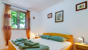 Un lit en bois avec des oreillers verts, une table de chevet avec une lampe et une fenêtre avec des rideaux.