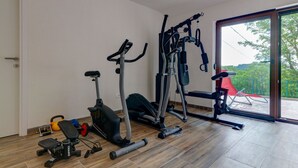 Une salle de sport à domicile équipée d’un vélo d’exercice, d’un appareil elliptique et de poids libres.