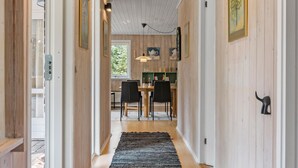 A hallway with wooden walls, a black rug, and a dining area with chairs and a table. - Cozy home in Nørre Nebel with sauna (Nørre Nebel)
