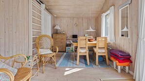 A cozy cabin interior with a wooden interior, a dining table with chairs, a bookshelf, and a small desk with a lamp. - Cozy home in Nørre Nebel with sauna (Nørre Nebel)