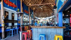 A bar with stools, a counter, and a thatched roof. - Oasis at Beach Villas | Walk to Siesta Key Beach, Multiple Balconies, Semi-Private Pool and Spa (Sarasota)