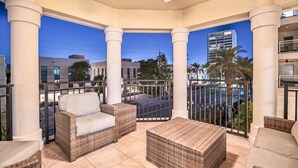 A covered outdoor seating area with wicker furniture, a ceiling fan, and a view of a cityscape at dusk. - Oasis at Beach Villas | Walk to Siesta Key Beach, Multiple Balconies, Semi-Private Pool and Spa (Sarasota)