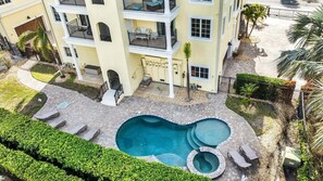 A multi-story building with a swimming pool, outdoor seating, and a well-maintained garden.
