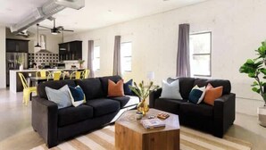 A modern living room with two black sofas, a wooden coffee table, and a dining area with yellow chairs. - Nova-400k Backyard! Old Town and Ent District! (Scottsdale)