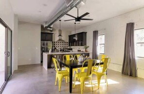 Una cucina moderna con isola centrale, sedie gialle attorno a un tavolo e una ventola a soffitto.