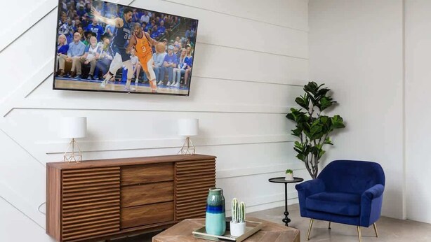 A modern living room with a wooden cabinet, a blue armchair, a coffee table, and a TV mounted on the wall. - Nova-400k Backyard! Old Town and Ent District! (Scottsdale)
