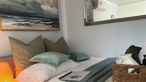 A neatly arranged bedroom with a bed, pillows, a bedside lamp, a mirror, and a painting on the wall. - Beach Serenity 1

Share

Save
 (Brighton-Le-Sands)