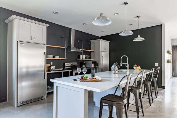 A modern kitchen with a central island, stainless steel appliances, and pendant lighting. - Synergy 2 Pools Directly in the Middle of Old Town (Scottsdale)