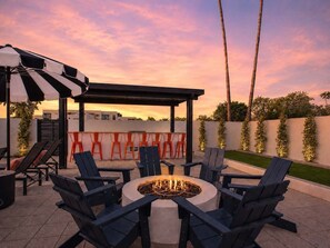 Un espacio de patio con un brasero, asientos al aire libre y una pérgola.