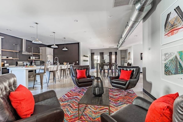 A modern living room with leather sofas, a coffee table, and a colorful rug.
