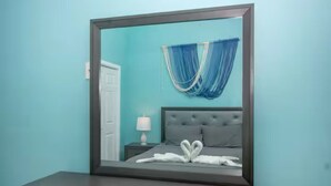 Un dormitorio con una cama, una mesita de noche, una lámpara y una ventana con cortinas.