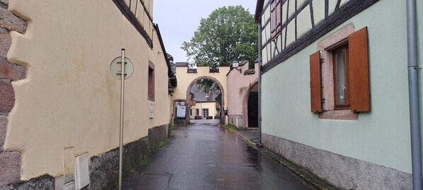 A narrow alleyway between buildings with a wet pavement, suggesting recent rain.