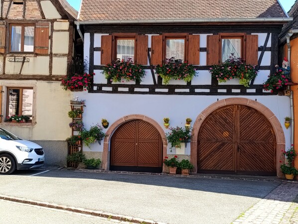 A traditional half-timbered house with two large wooden doors and a balcony with flower boxes.