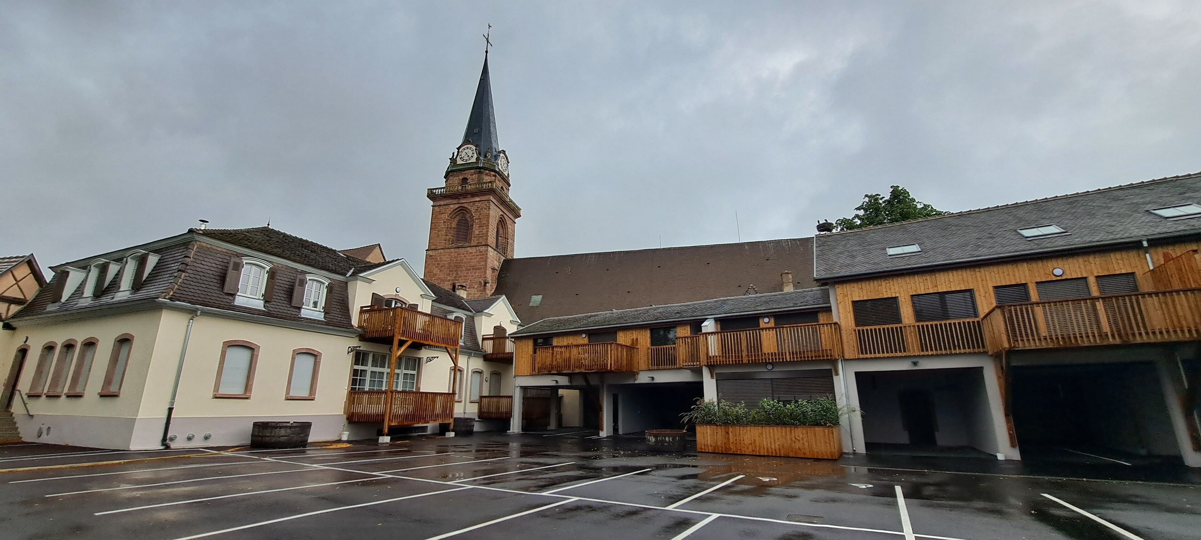 Een parkeerplaats met een kerk en woongebouwen.