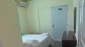 Une chambre d’hôtel avec un lit, un bureau, une chaise, une armoire et une porte.