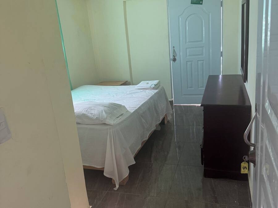 Una habitación de hotel con cama, escritorio, silla, armario y puerta.