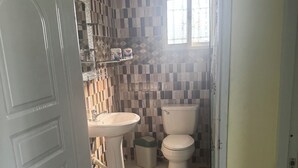 Une salle de bain avec un sol carrelé, un lavabo, des toilettes et un miroir.