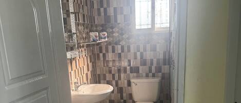 Une salle de bain avec un sol carrelé, un lavabo, des toilettes et un miroir.