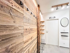 A modern interior with a wooden wall, a door labeled "CASA IN," and a circular mirror on the wall.
