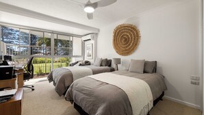 A bedroom with two beds, a desk, and a ceiling fan.