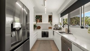 A modern kitchen with white cabinetry, stainless steel appliances, a built-in oven, and a dishwasher.