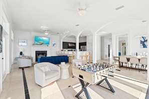 A spacious living room with a foosball table, a fireplace, and a dining area with a large table and chairs. - 🐚 Cornerstone Cove | Pool & Private Beach Access | Dog Friendly* | FREE Beach Chair Svc ☀️ (Miramar Beach)