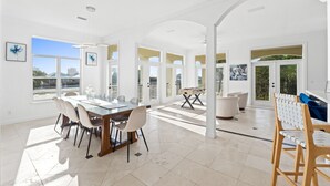 Un comedor amplio con una mesa y sillas de vidrio, una mesa de fútbol de mesa y vistas al exterior.