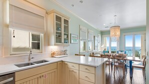 A spacious kitchen with a large island, wooden cabinets, and a view to the outside. - 🌊 Serenity by the Sea | Beach Front | FREE Pool Heating | Elevator & FREE Excursions (Miramar Beach)