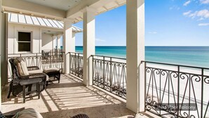 A covered balcony with outdoor furniture, a view of the ocean, and a clear sky. - 🌊 Serenity by the Sea | Beach Front | FREE Pool Heating | Elevator & FREE Excursions (Miramar Beach)
