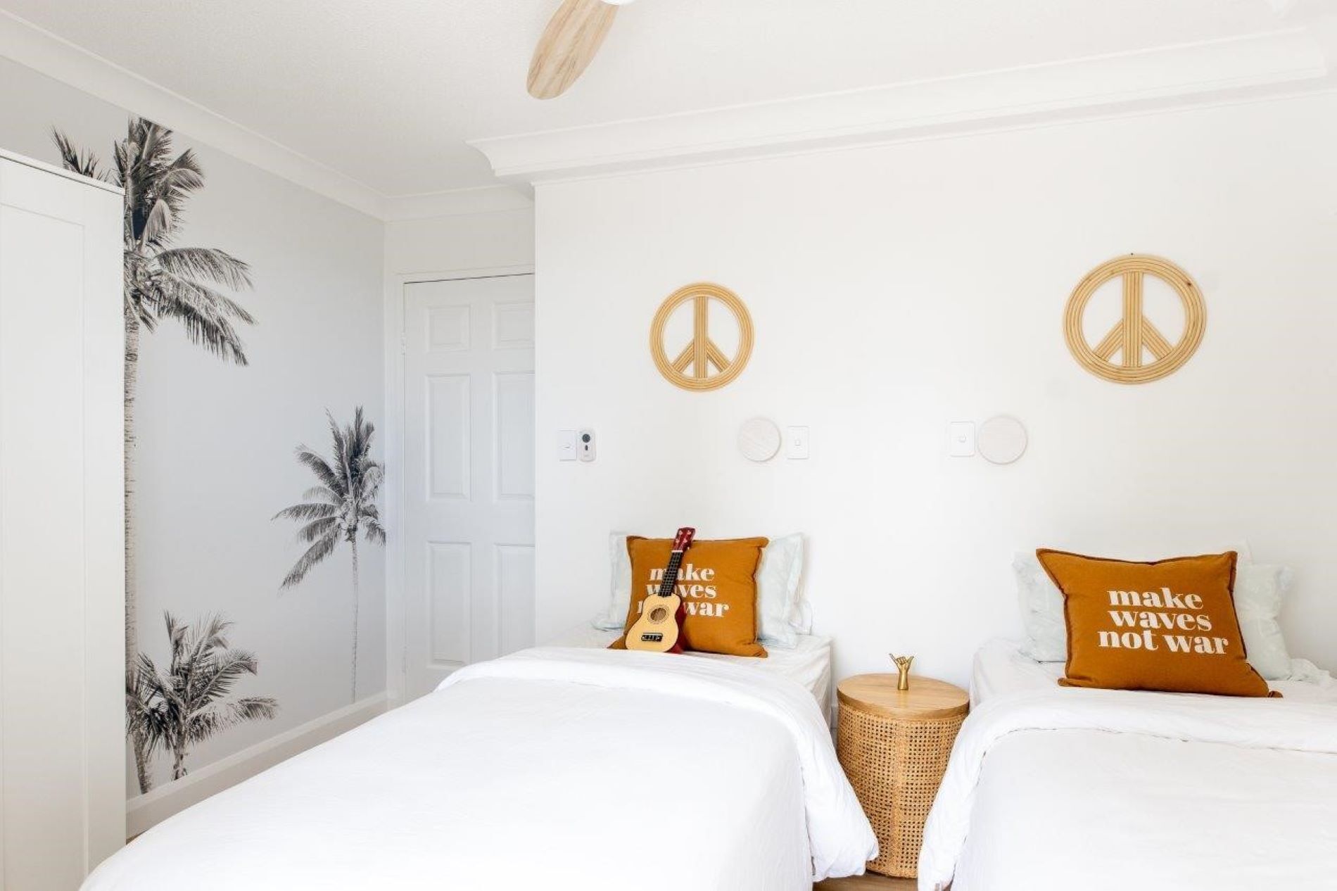 Quarto com duas camas, uma porta e dois símbolos da paz na parede.
