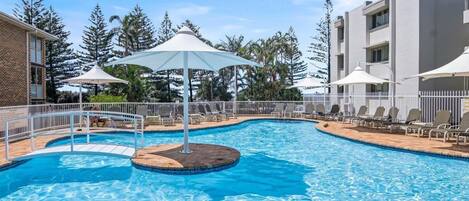 Una piscina cubierta, una piscina al aire libre, sombrillas