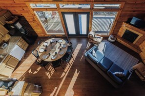 A cabin interior with a dining area, kitchen, and seating space.