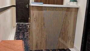 A szálloda recepciója egy fa pulttal, egy órával és egy táblával van felszerelve, amelyen a bejelentkezési időpontok szerepelnek.