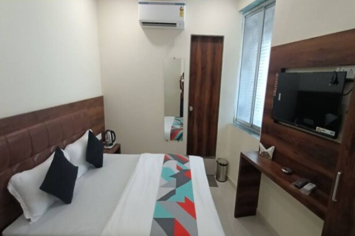 A hotel room with a bed, a TV, a desk, and a window.