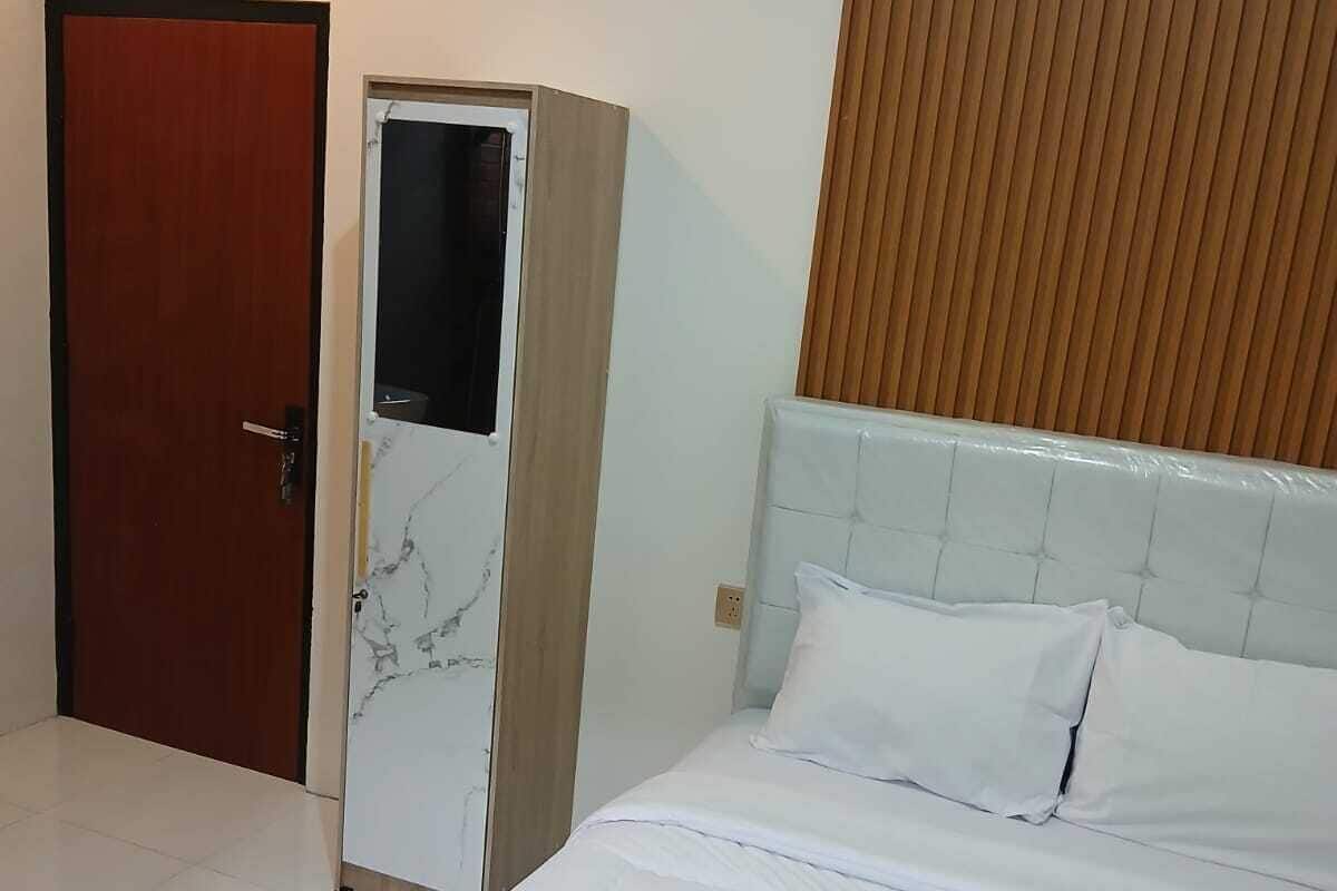Hotellihuone, jossa on sänky, vaatekaappi ja puupanelilla verhoiltu seinä.