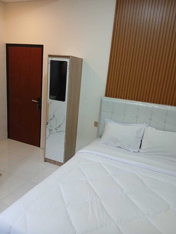 Une chambre d’hôtel avec un lit, une armoire et un mur recouvert de panneaux de bois.
