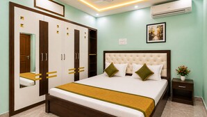 A bedroom with a bed, wardrobe, bedside table, and an air conditioning unit. - Shiv Kashi P Guest House By Glitz Hotels (Varanasi)