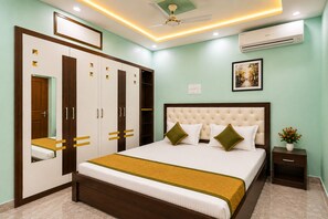 A bedroom with a bed, wardrobe, bedside table, and an air conditioning unit. - Shiv Kashi P Guest House By Glitz Hotels (Varanasi)